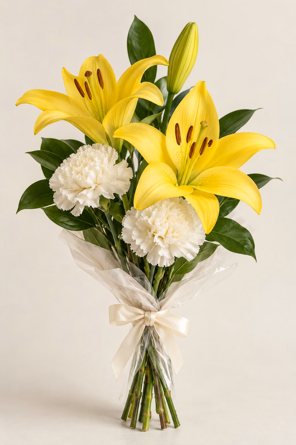 Lily Sunshine Budget Bouquet: 1 yellow lily stem with 2 open blooms and 1 closed bud, 2 white standard carnations, a few salal leaves. Traditionally hand-tied with simple tissue and clear wrapping, finished with a coordinating ribbon.